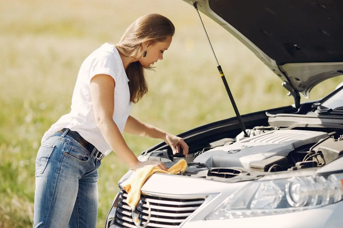 A stranded driver beside a broken-down car handling an unexpected repair